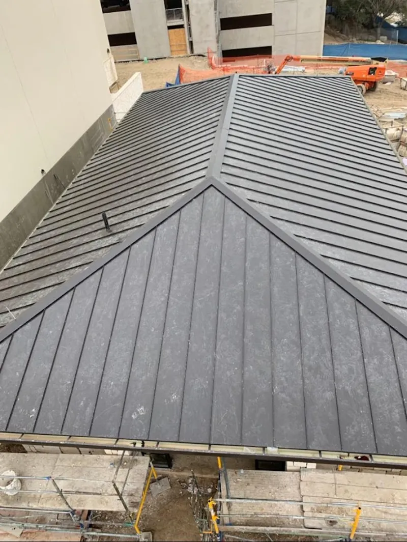 Commercial metal roof construction with crane equipment in Pflugerville